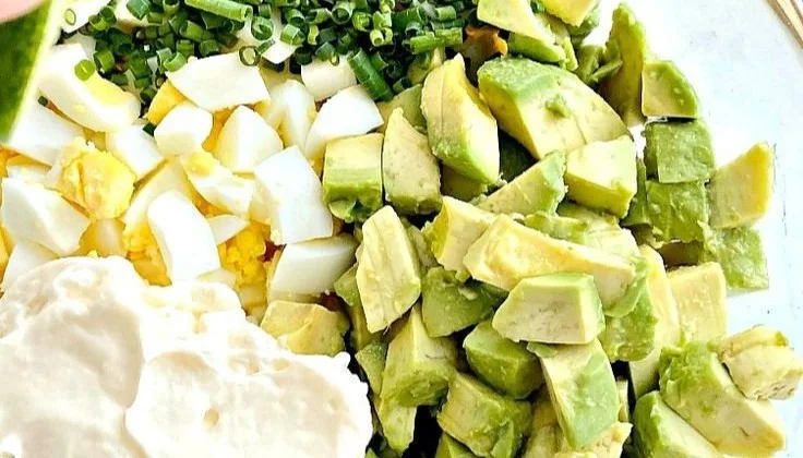 Keto avocado egg salad served in a bowl with fresh herbs and ingredients.